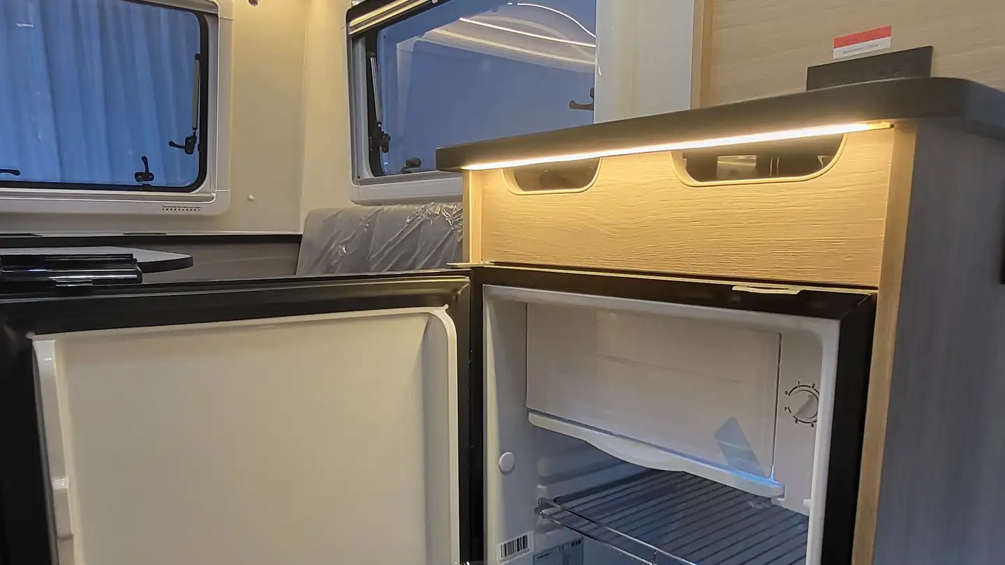 Open compact refrigerator built into a wooden caravan kitchen unit
