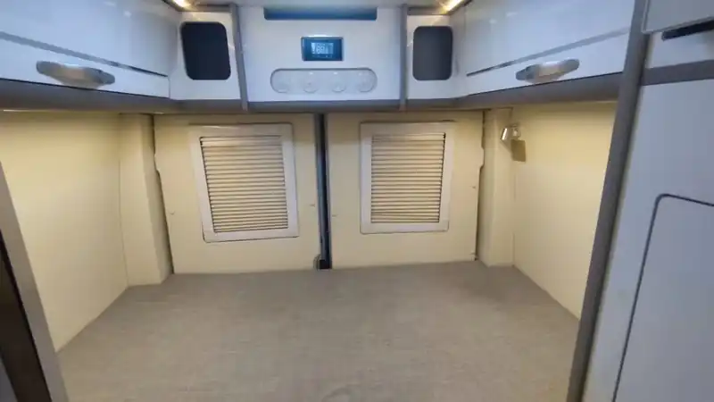 Bare interior of a camper conversion with lined walls and windows before furnishing