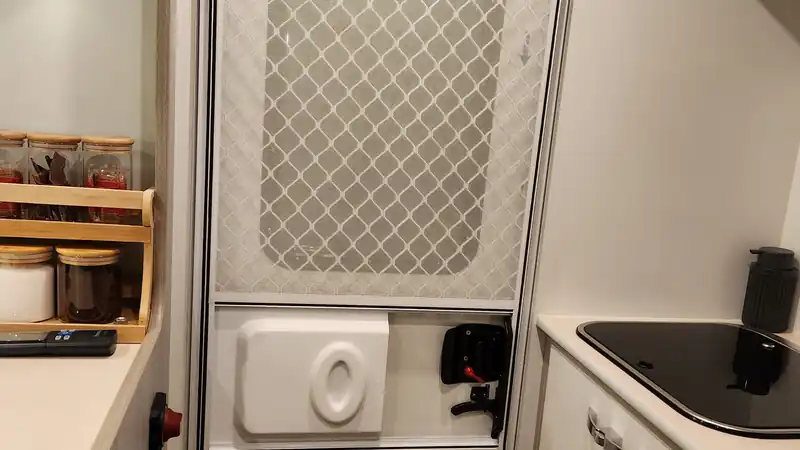 Campervan entry door with a security screen door, viewed from the kitchen