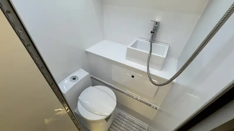 Compact camper bathroom with a cassette-style toilet, small sink and shower