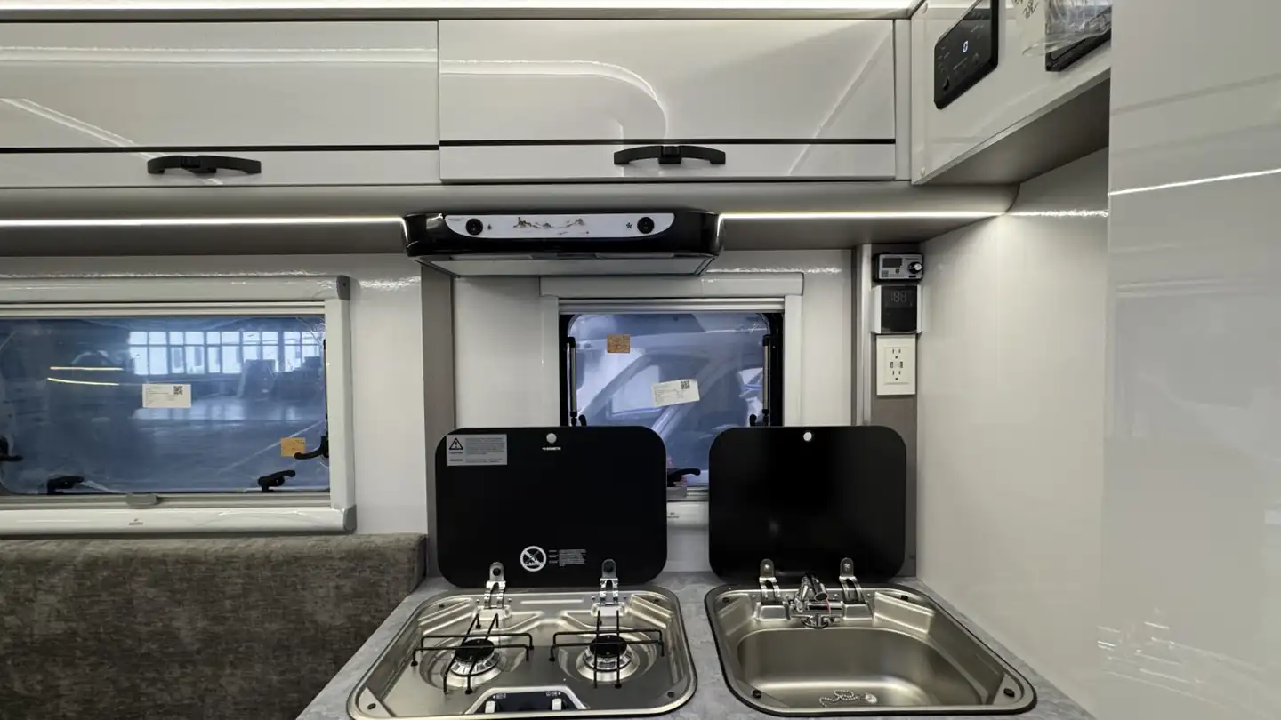 Compact kitchen in a Bijanco pickup camper with a stainless sink and two-burner stove