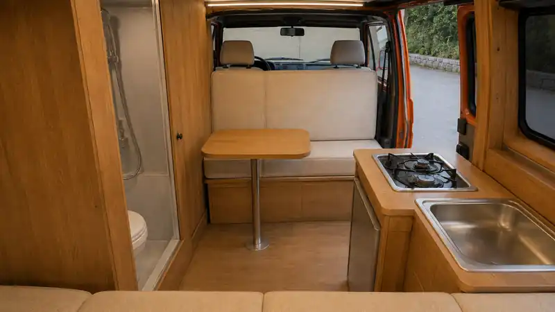 Interior of a locally converted van with a wooden kitchen, bench seat and table