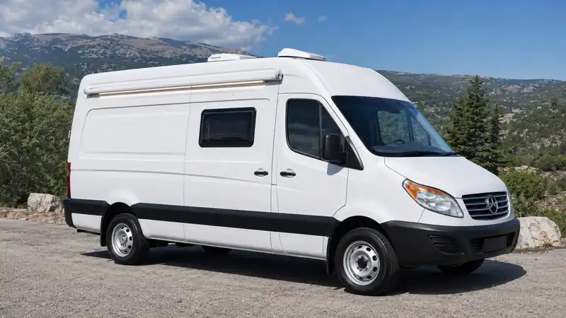 White high-roof panel van campervan parked in front of mountains